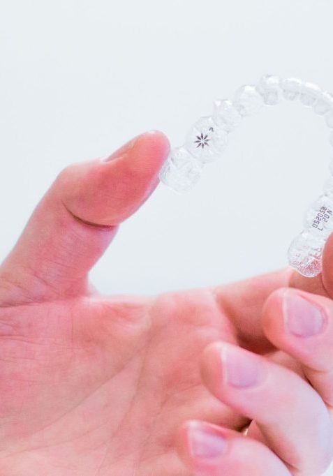 hand-holding-invisalign-aligners hand holding Invisalign aligner